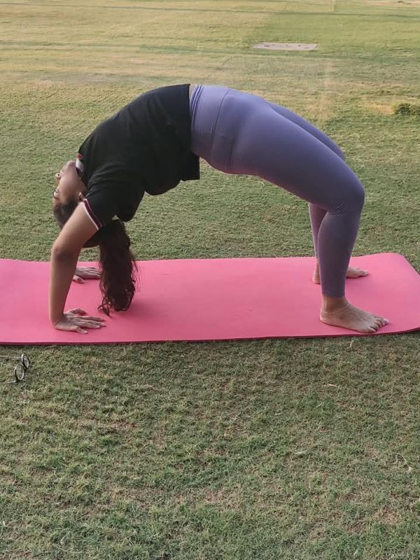 Student practising Chakrasana (wheel pose) in the park